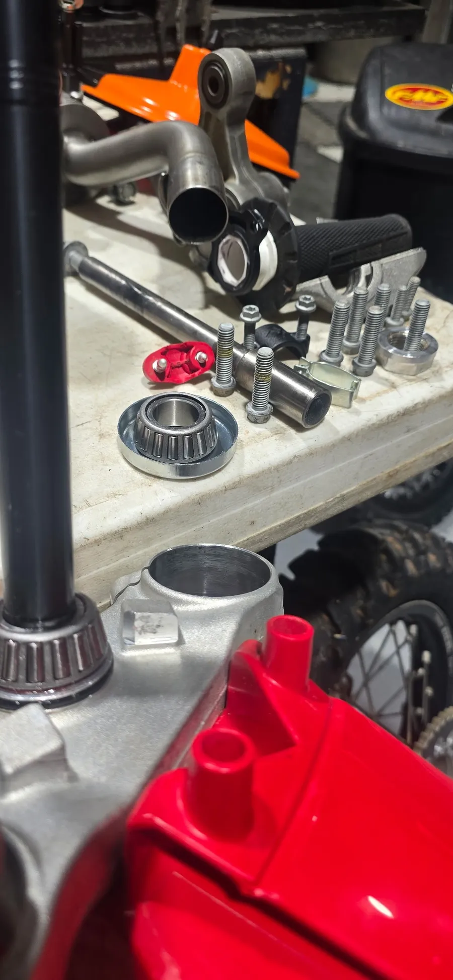 Triple clamp, fresh bearings, and hardware laid out on the bench