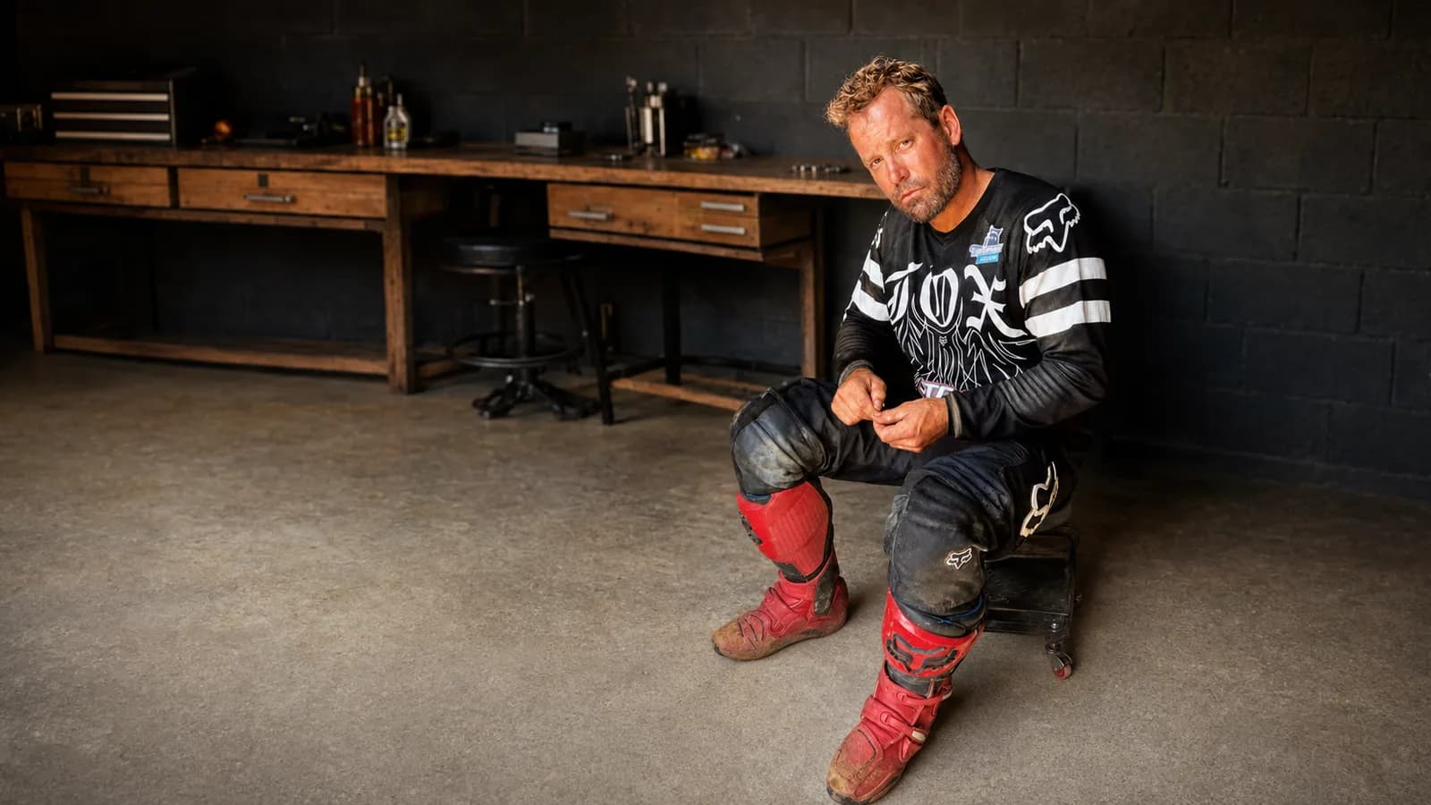 Mike Stevenson in motocross gear seated in a workshop