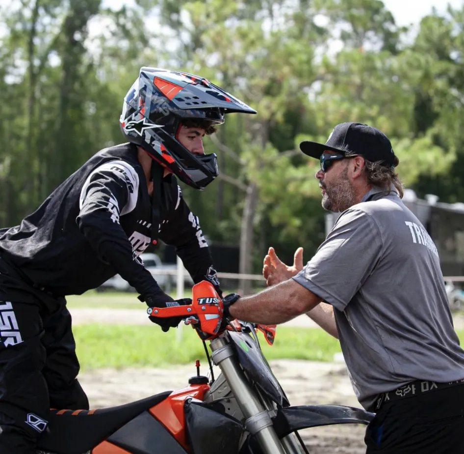 Mike coaching a rider one-on-one at the handlebars between laps